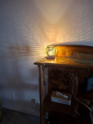 Ein Holztisch mit einer Zierlampe, einer Taschentuchbox und einer Steckdose an der Wand.