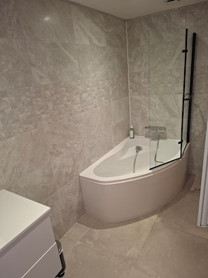 Ein modernes Badezimmer mit einer freistehenden Badewanne, einer Duschkabine aus Glas und einem weißen Waschtisch.