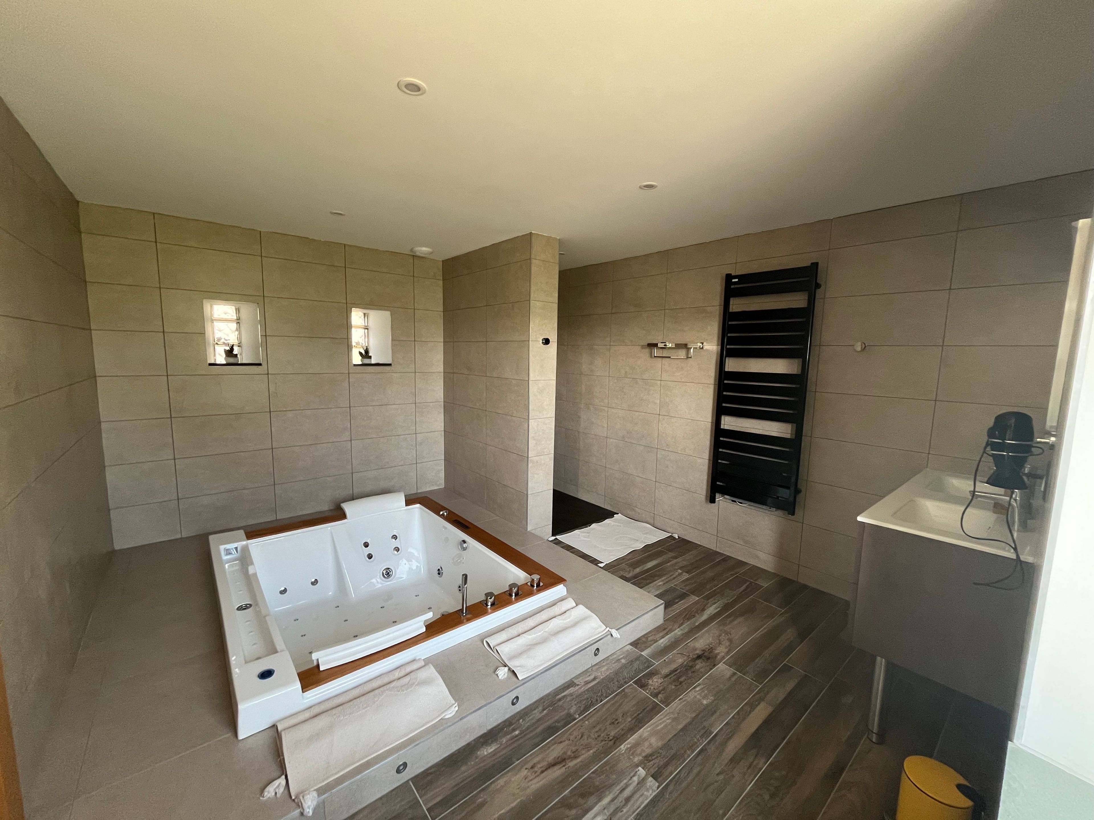 Un baño moderno con una bañera grande, un perchero y una zona de ducha.