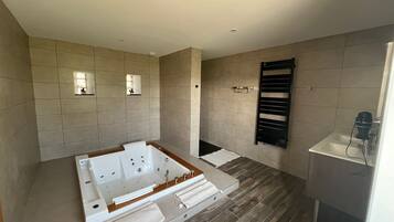 Un baño moderno con una bañera grande, un perchero y una zona de ducha.