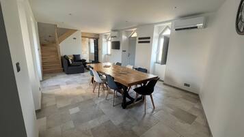 Un interior moderno con comedor que incluye una mesa y sillas de madera, una escalera y una sala de estar con sofá.