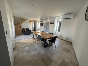 Un interior moderno con comedor que incluye una mesa y sillas de madera, una escalera y una sala de estar con sofá.