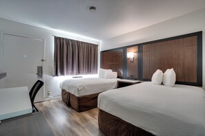 A hotel room with two beds, a desk, and a chair. - 1625 French Camp Turnpike (Stockton)