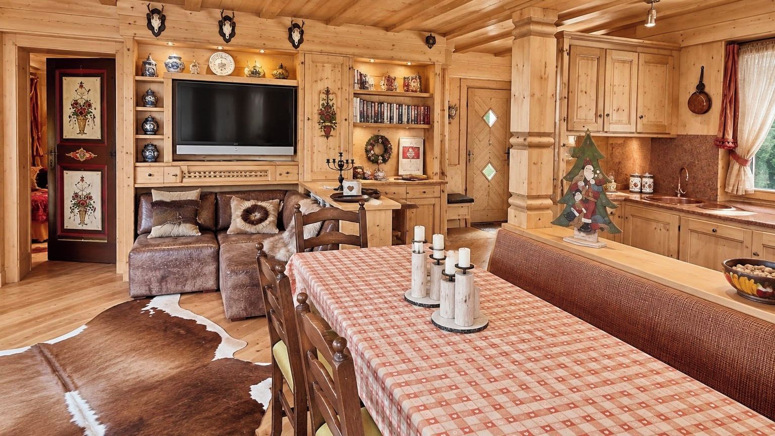 A cozy wooden interior with a dining table, benches, and a television.