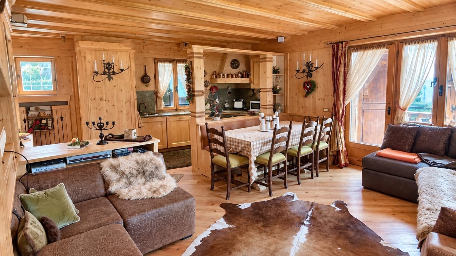 A cozy cabin interior with a dining area, a sofa, and a large fur rug.
