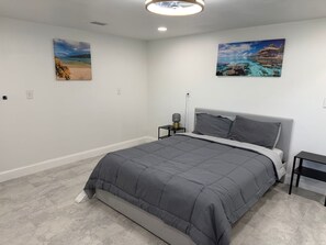 Et soveværelse med seng, et natbord, en lampe og to billeder på væggen.