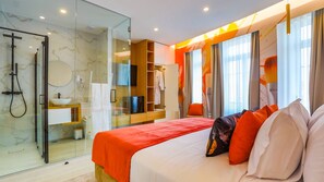 Une chambre d’hôtel avec une douche en verre, un lit avec une literie rouge et un grand miroir.