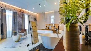 Une salle de bain moderne avec une baignoire sur pieds, une douche à l’italienne et un grand miroir.