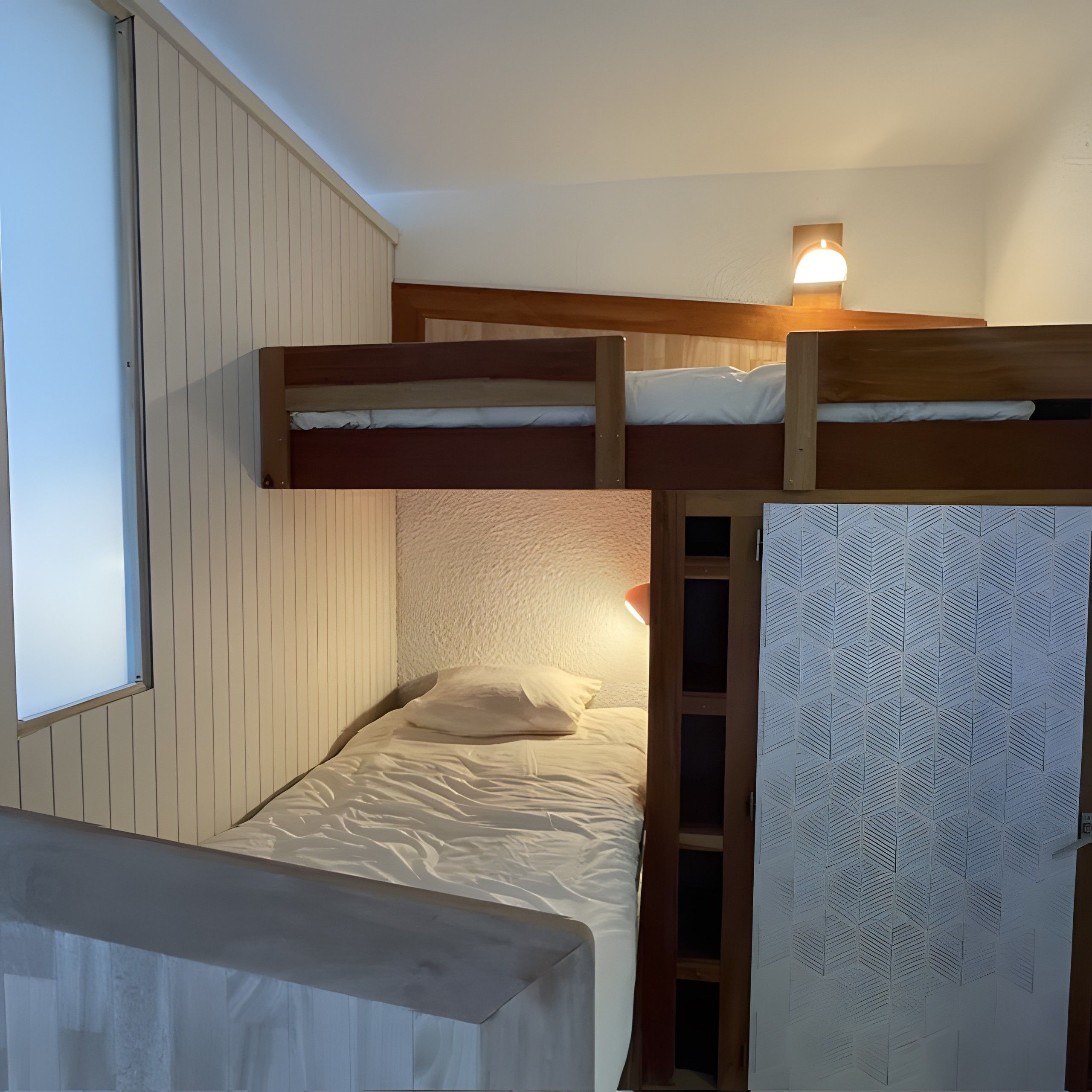 A bunk bed with a headboard, a window, and a wall with a geometric pattern.