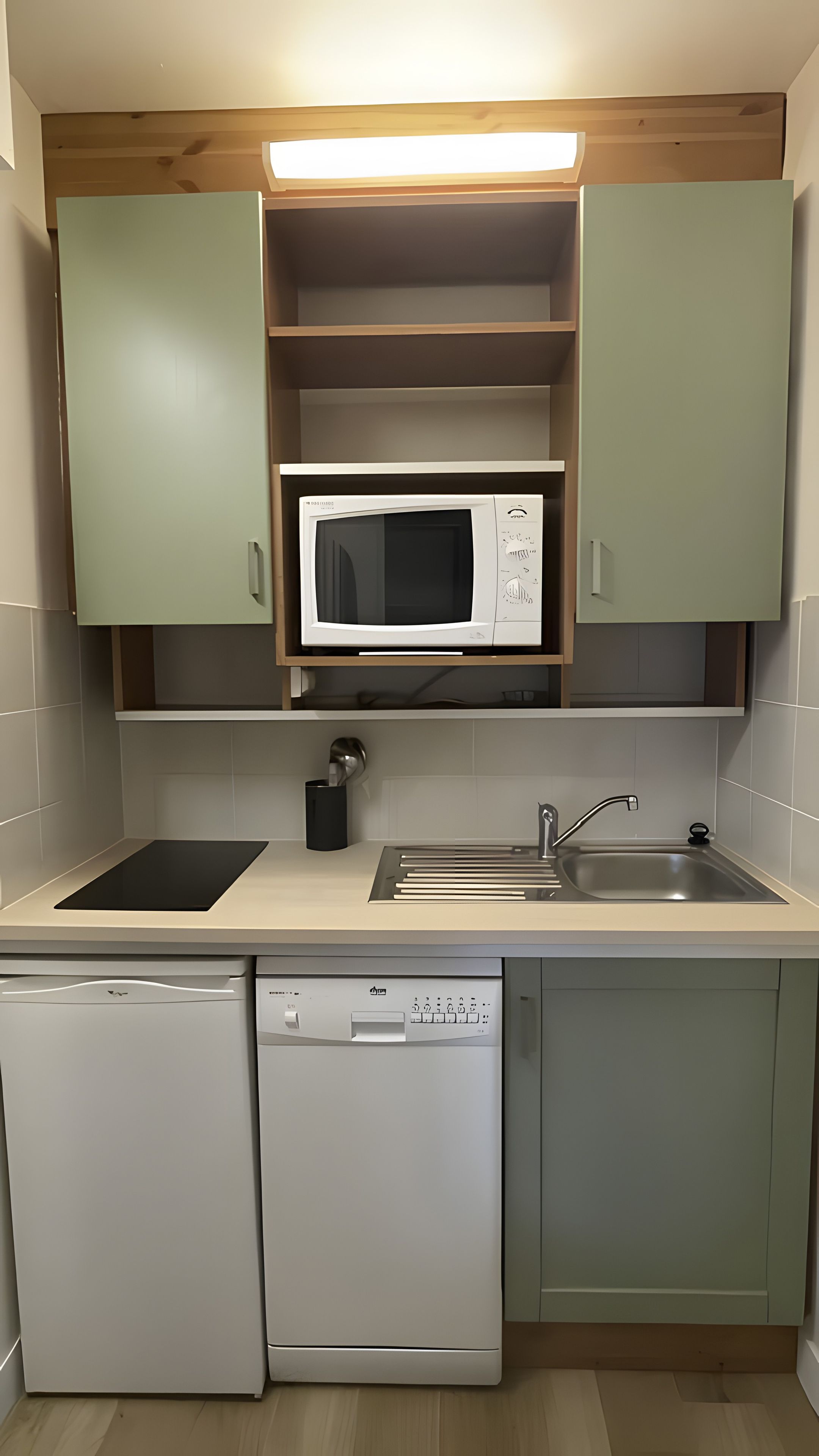 A compact kitchen with a microwave, sink, and dishwasher.