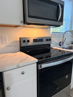 Une cuisine équipée d’un four à micro-ondes, d’un four et d’une plaque de cuisson intégrés.