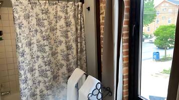 Un baño con cortina de ducha, toallero y ventana con vistas al exterior.
