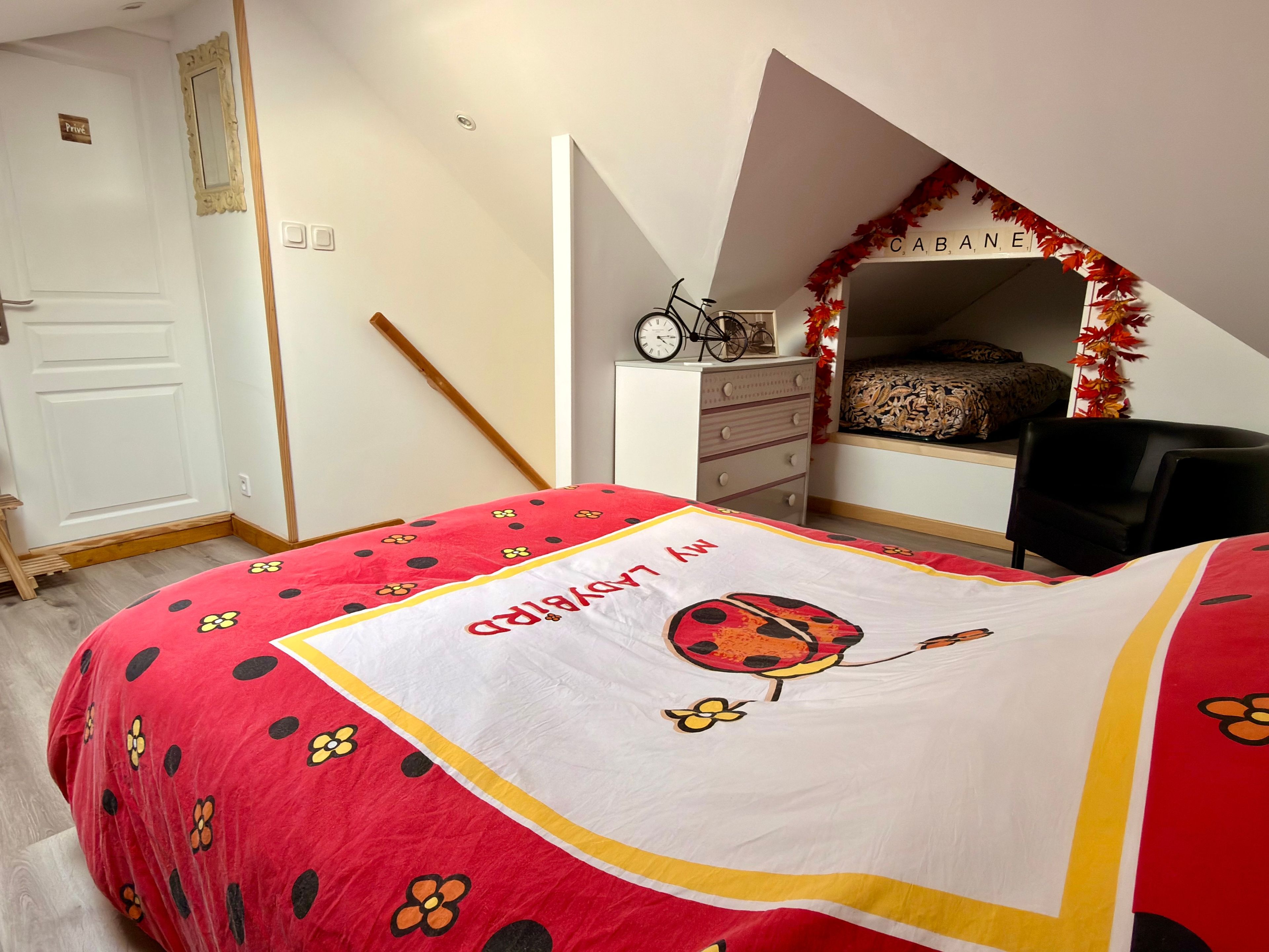 Un dormitori amb un llit, una petita taula de nit, una cadira i una finestra que dona al paisatge exterior.