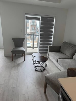 Uma sala de estar moderna com um sofá cinzento, uma poltrona a combinar e uma mesa de centro de metal preta e singular.