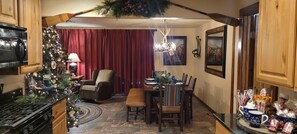 A cozy kitchen with a dining area, wooden cabinets, a Christmas tree, and holiday decorations.