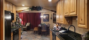 A kitchen with wooden cabinets, a dining area with a red curtain, and a Christmas tree.