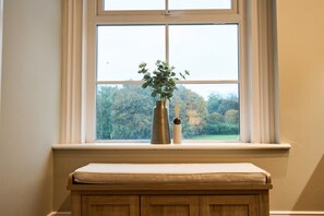 Une fenêtre donnant sur des arbres, avec un banc en contrebas.