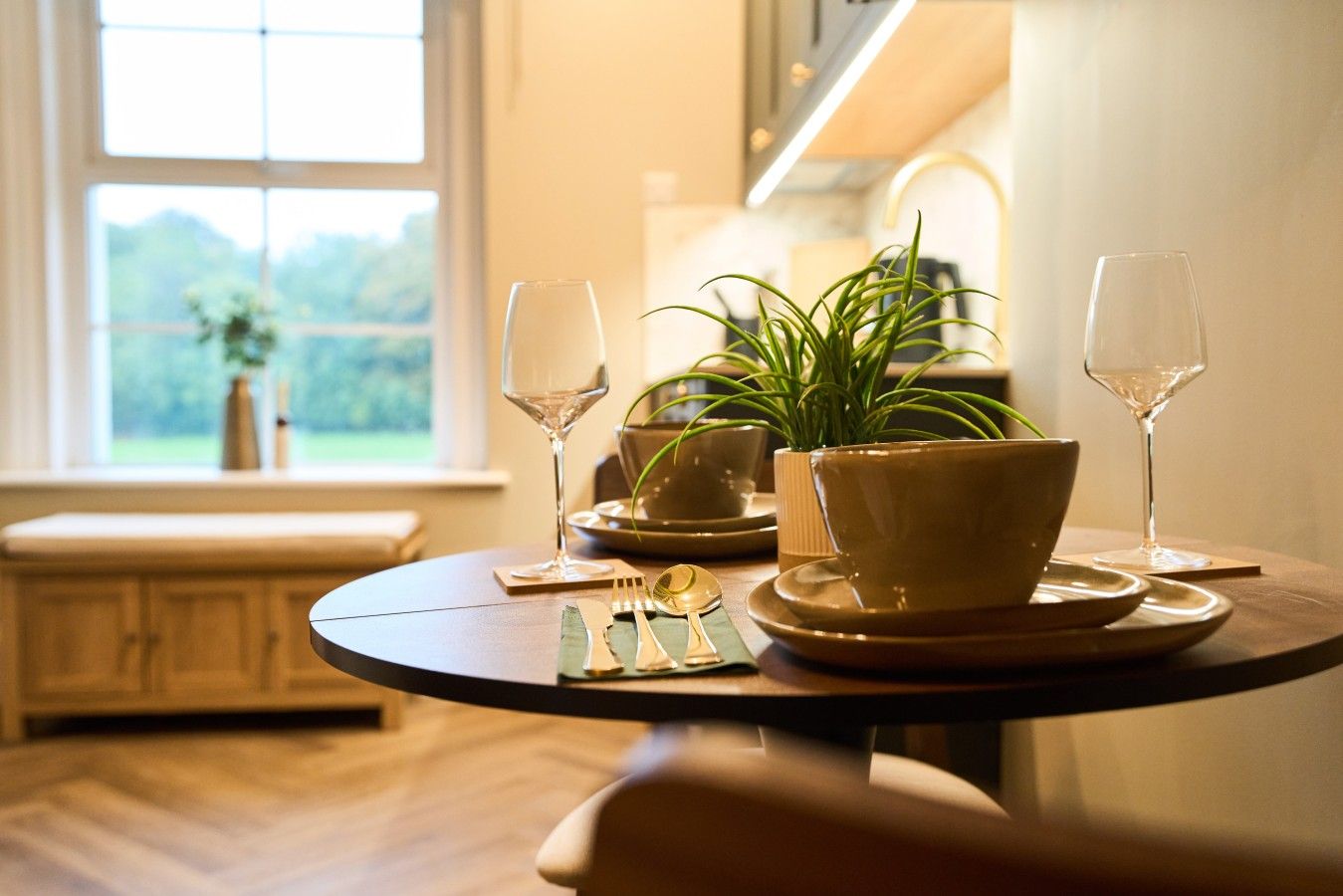 Une table à manger avec un saladier, des assiettes, des couverts et deux verres à vin.