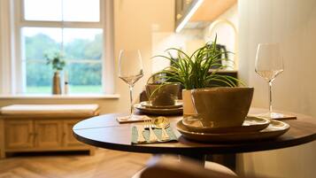 Une table à manger avec un saladier, des assiettes, des couverts et deux verres à vin.