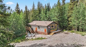 Une cabane dotée d’une terrasse, d’un espace salon extérieur et d’une allée en gravier.