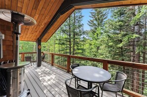 Une terrasse en bois avec une table et des chaises, donnant sur une forêt.