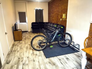 A room with a wooden floor, a black sofa, a bicycle, and a brick wall. - 1BR close to the Erie Canal Trail, and across from Lunkenheimer Craft Brewery (Weedsport)