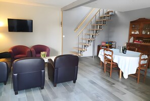 Een moderne woonkamer met een eethoek, een trap en een flatscreen televisie.