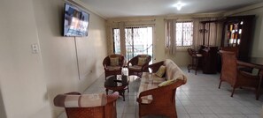 A living room with wicker furniture, a flat-screen TV mounted on the wall, and a view through the window. - New Listing (Salinas)