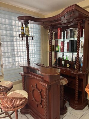 A bar area with a wooden bar counter, a mirror, and shelves with bottles. - New Listing (Salinas)