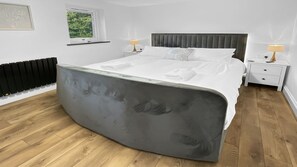 Un dormitorio moderno con una cama grande, un radiador, una ventana y lámparas de noche.