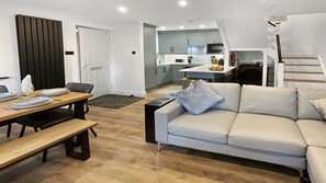 Una sala de estar moderna con un sofá, una mesa de comedor con sillas y una cocina al fondo.