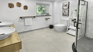 Un baño moderno con inodoro, bidé y cabina de ducha de vidrio.