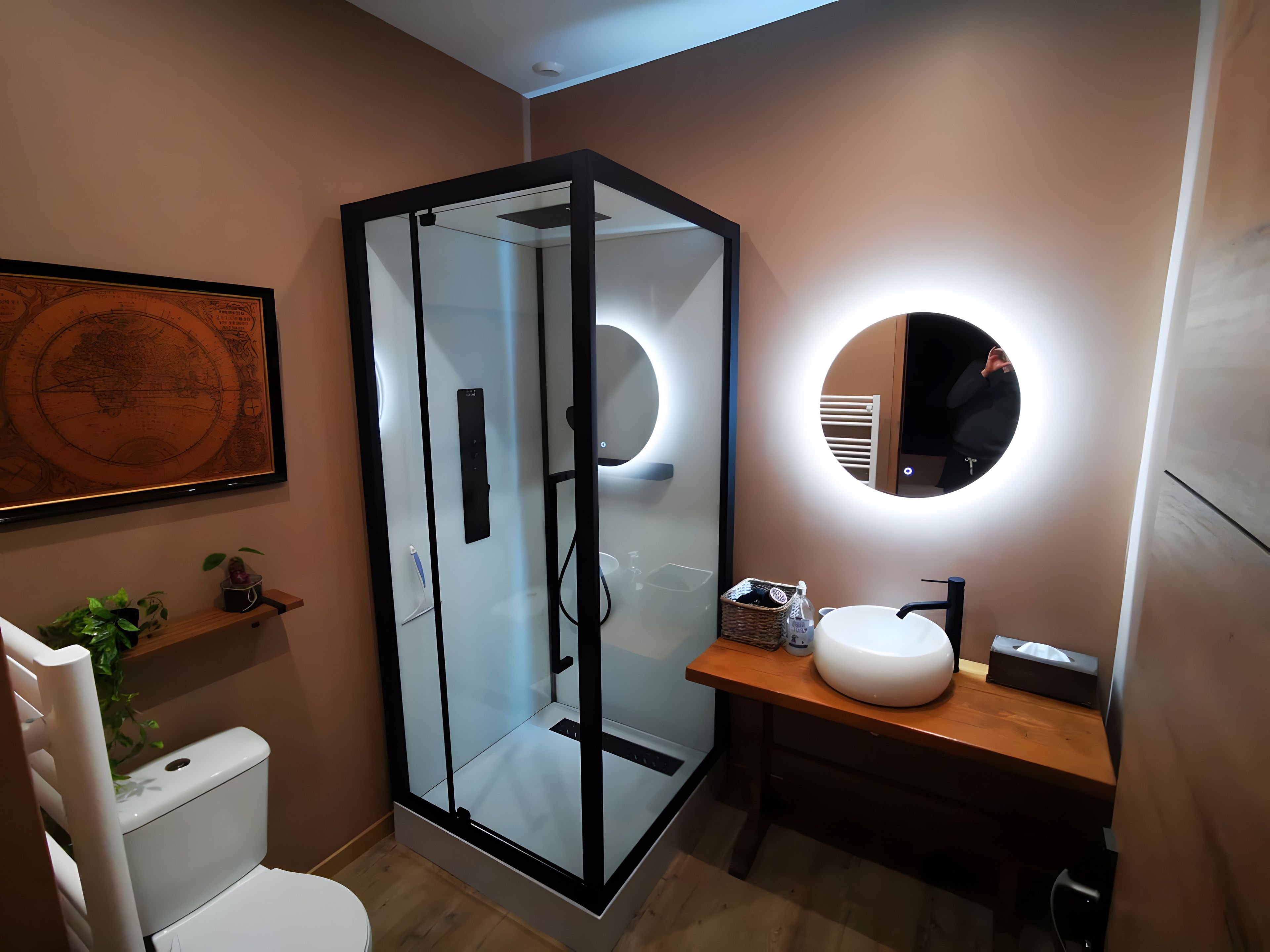 Une salle de bain moderne avec une douche à parois de verre, un miroir rond et un lavabo blanc.