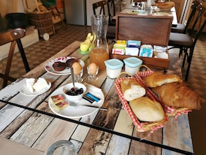 Une table en bois sur laquelle sont disposés des aliments pour le petit-déjeuner, notamment du pain, des œufs et des condiments.
