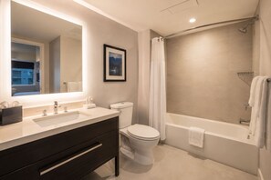 Ein modernes Badezimmer mit großem Spiegel, zwei Waschbecken, Toilette und Badewanne.