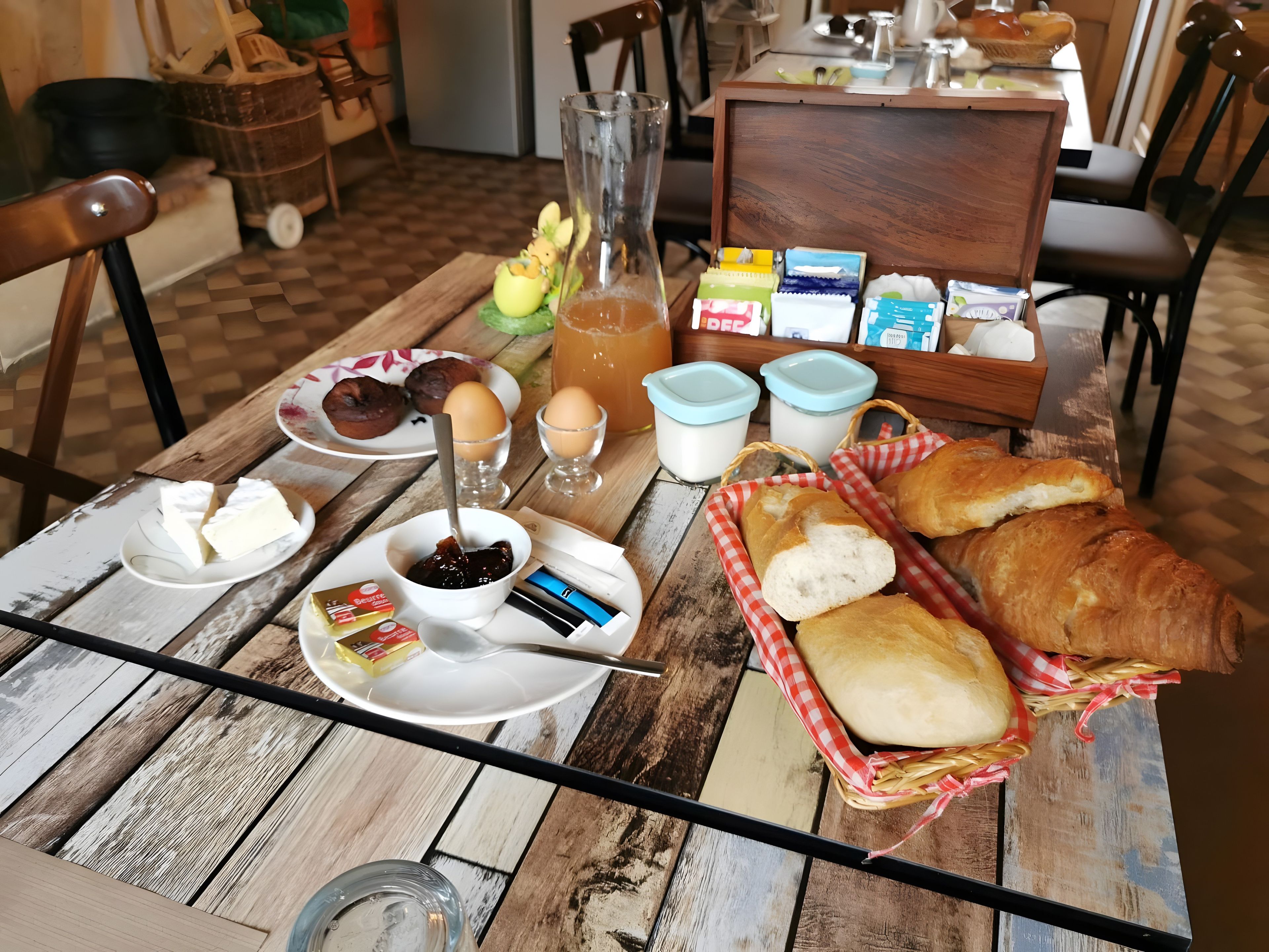 Een houten tafel met ontbijtartikelen, zoals brood, eieren en toevoegingen.