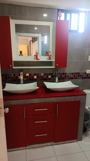 A bathroom with two sinks, red cabinets, a mirror, and a tiled backsplash. - New Listing (Salinas)