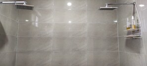 A shower area with a tiled wall, a handheld showerhead, and a wall-mounted showerhead. - New Listing (Salinas)