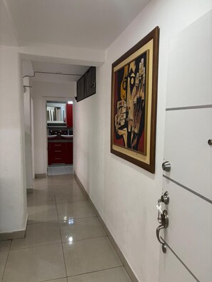 A hallway with a tiled floor, a door with a key lock, and a painting on the wall. - New Listing (Salinas)