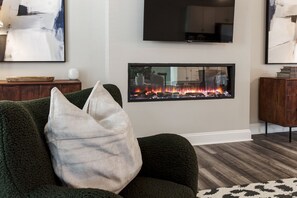 A living room with a fireplace, a sofa, and a television mounted on the wall. - Spacious Raleigh Retreat with King Suite, Workspace & Sleeps 6 (Raleigh)