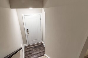 A hallway with a white door, a handrail, and a wooden floor. - Spacious Raleigh Retreat with King Suite, Workspace & Sleeps 6 (Raleigh)