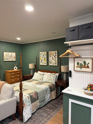 Un dormitorio con cama, cómoda, mesitas de noche, lámparas y decoración en la pared.