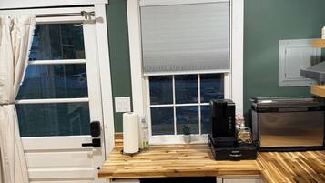 A compact kitchen with a built-in coffee maker, a mini-fridge, and a window with a view.