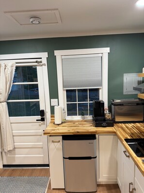 Cocina compacta con cafetera integrada, mini refrigerador y ventana con vistas.