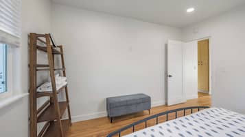 Ein Schlafzimmer mit einem Bett, einer Holzleiter, einer Bank und einer Tür zu einem anderen Raum.