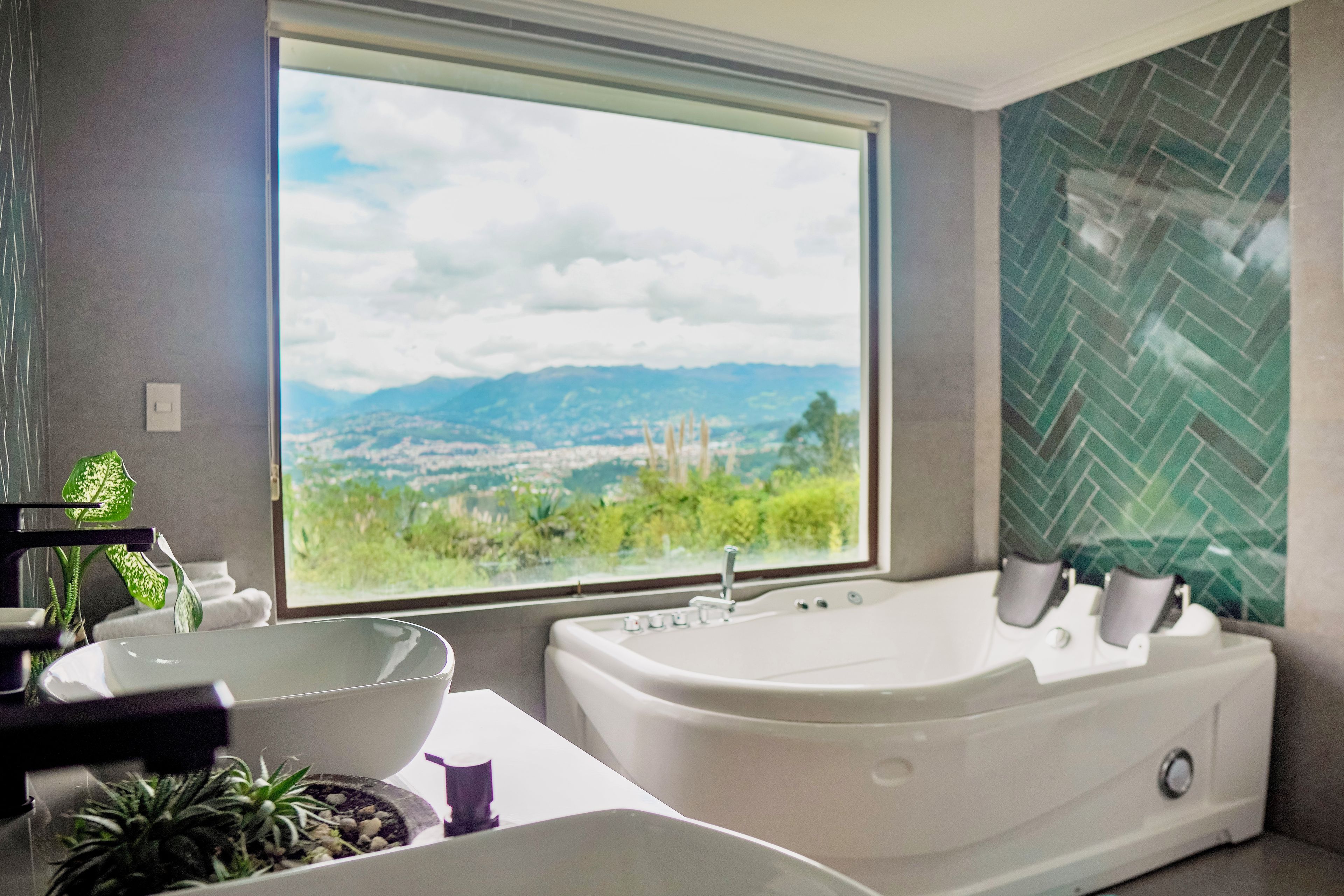 Ein Badezimmer mit großem Fenster, einer Badewanne, einem Waschbecken und einer Topfpflanze.