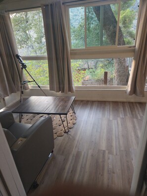 A room with a large window, a tripod, a sofa, and a wooden floor. - Charming 3-bedroom house with AC in lovely Three Rivers (Three Rivers)