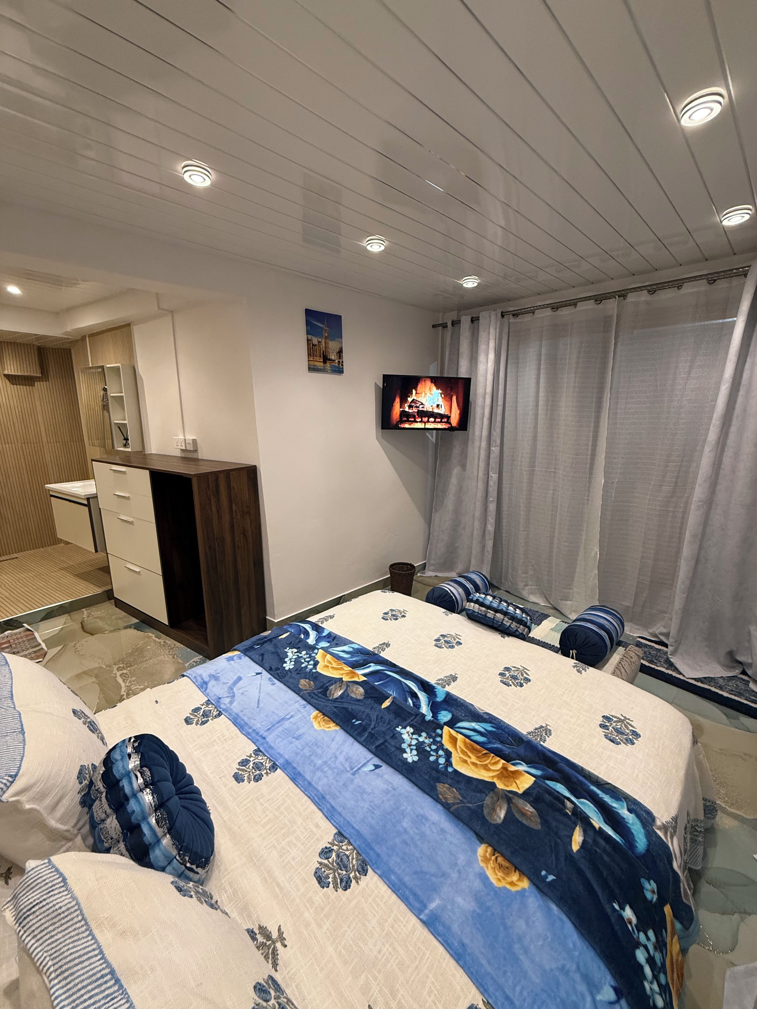 Ett hotellrum med en säng, en TV, ett skrivbord och ett badrum.