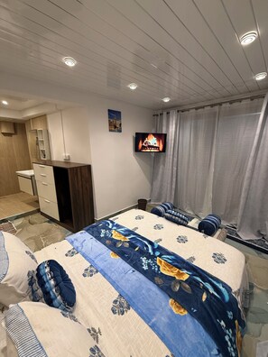 Ett hotellrum med en säng, en TV, ett skrivbord och ett badrum.