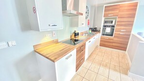 Cozinha moderna com bancadas de madeira, armários brancos e eletrodomésticos de aço inoxidável.